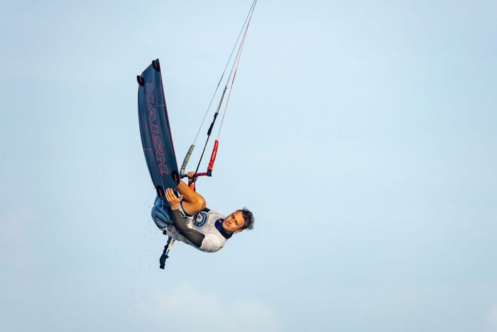 Thrilling kitesurfing trick performed midair, showcasing skill and adrenaline.