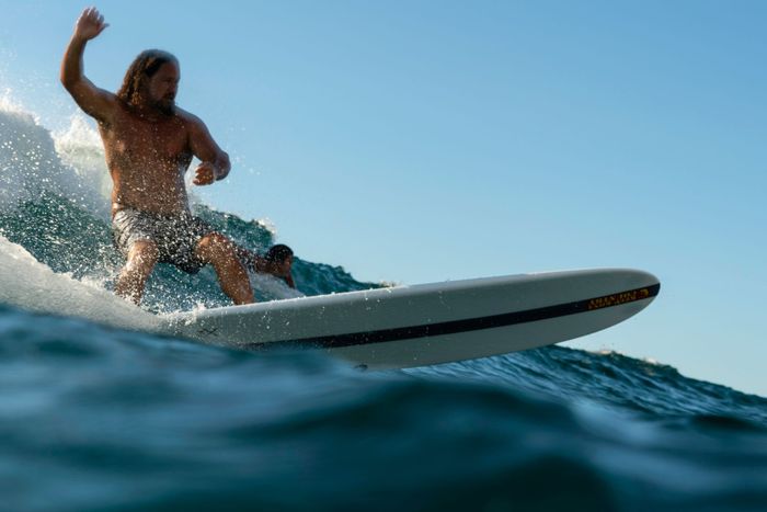 Man enjoying a thrilling surf ride on the waves at Hilo, Hawaii coast.