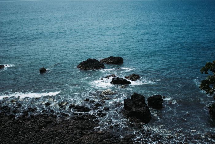 A breathtaking view of the rocky coastline and deep blue ocean in Jacó, Costa Rica.
