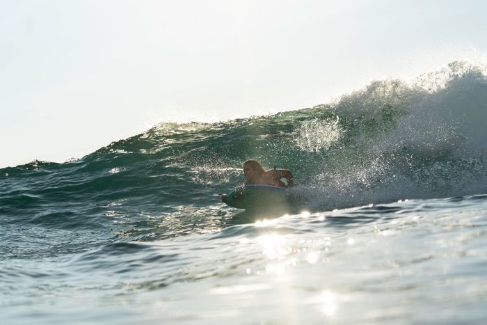 Dynamic shot of a surfer riding a wave in Hilo, Hawaii during a sunny day.