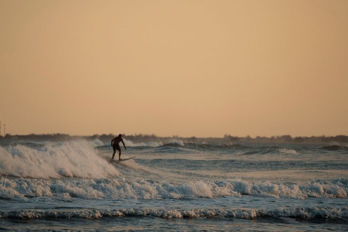 A lone surfer expertly navigates sunset waves, capturing the thrill of ocean adventure.