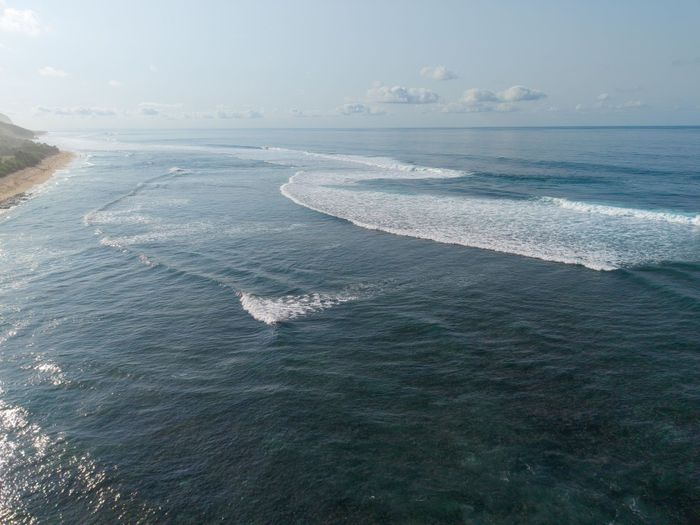 A breathtaking aerial shot of the clear blue ocean waves along the coast of Bali, Indonesia.