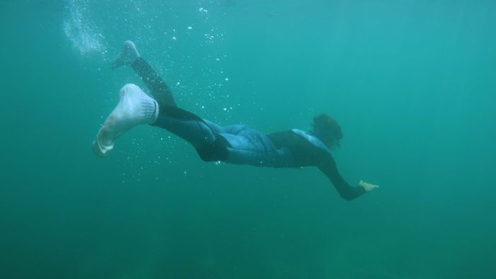 An underwater diver wearing a wetsuit explores the ocean depths in an adventurous scene.