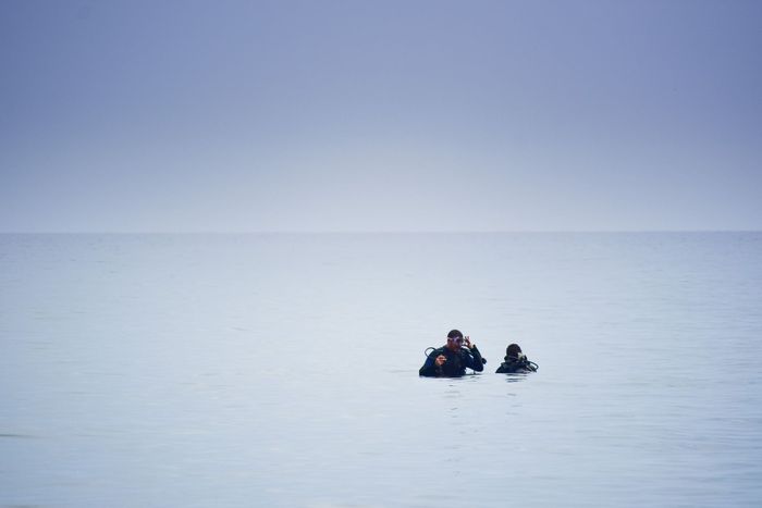 Two scuba divers in serene ocean, enjoying a tranquil dive under a clear blue sky.