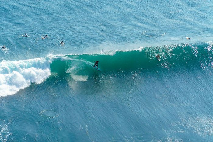 Exciting aerial shot of surfers catching waves in Bali, Indonesia.