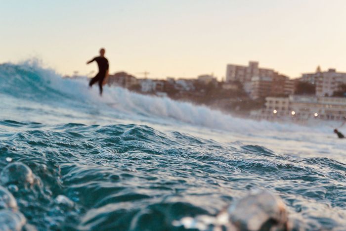 A surfer rides waves at Bondi Beach, Sydney, during a stunning day.
