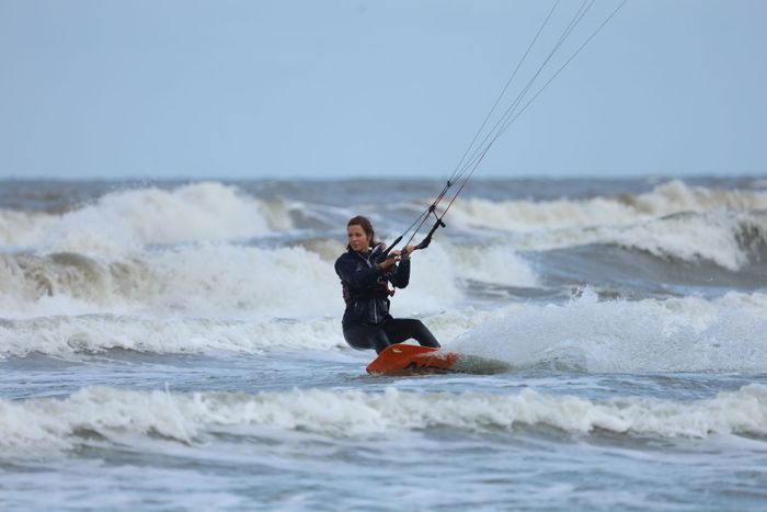 Woman kitesurfing on ocean waves, showcasing thrilling water sports adventure.