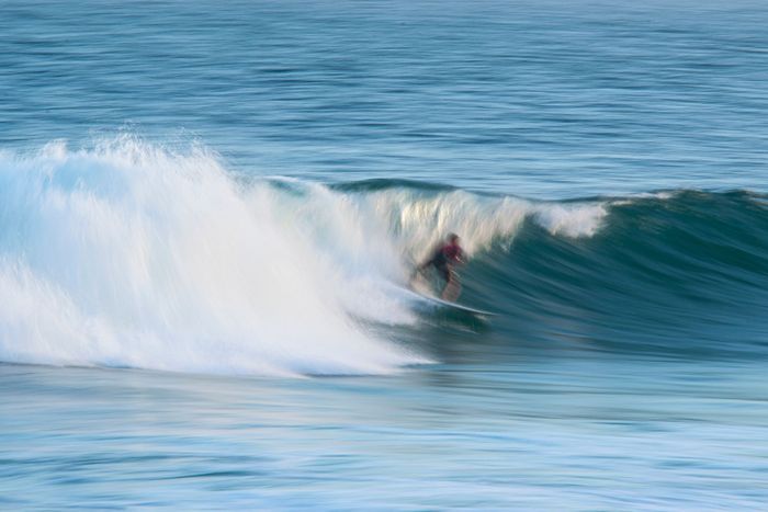 Exciting scene of a surfer riding the powerful waves of Rio de Janeiro with motion blur capturing the action.