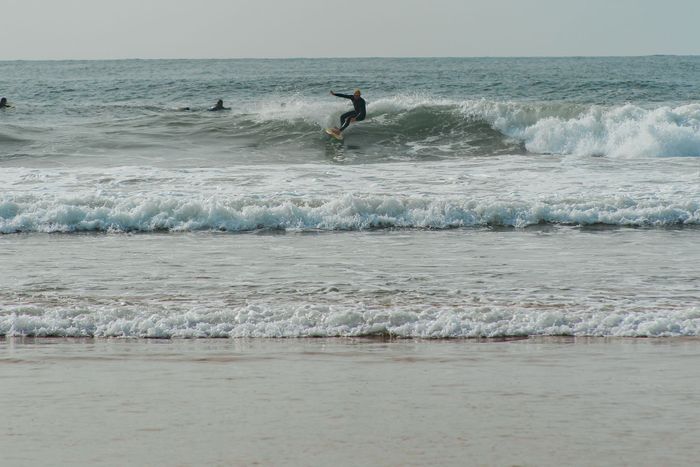 A surfer skillfully riding a wave on a tranquil beach, ideal for summer vibes.