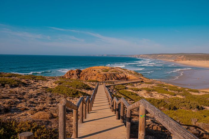 Wooden boardwalk leading to the stunning Praia da Bordeira beach in Portugal.