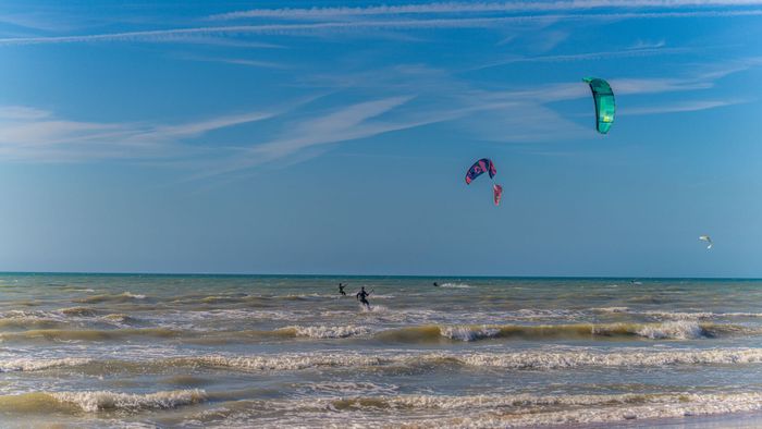 Thrilling kiteboarding scene on a sunny day with colorful kites soaring over the ocean waves.