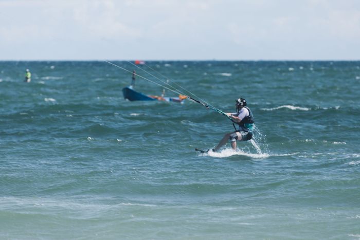 A thrilling moment captured of a kitesurfer riding waves on a sunny day at sea.