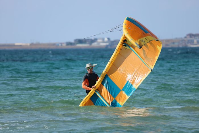 Kitesurfer enjoying a sunny day with vibrant kite in the ocean. Outdoor water sport activity.