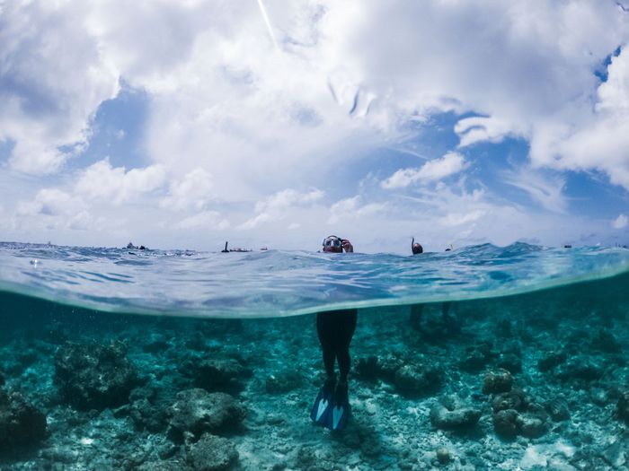 Anonymous person in snorkeling mask goggles and flippers standing in turquoise seawater on sunny summer day