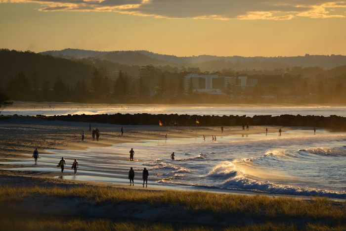 Stunning sunset over Coolangatta Beach in Australia, capturing serene waves and beachgoers.