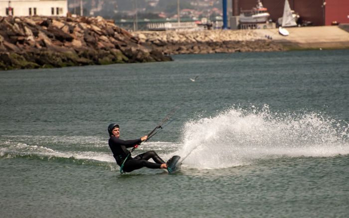 Dynamic action shot of a kite surfer gliding across the water in Viana do Castelo, Portugal.