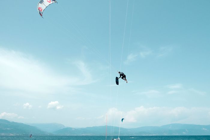 Kitesurfer performing an aerial stunt over the vibrant blue waters of Greece.