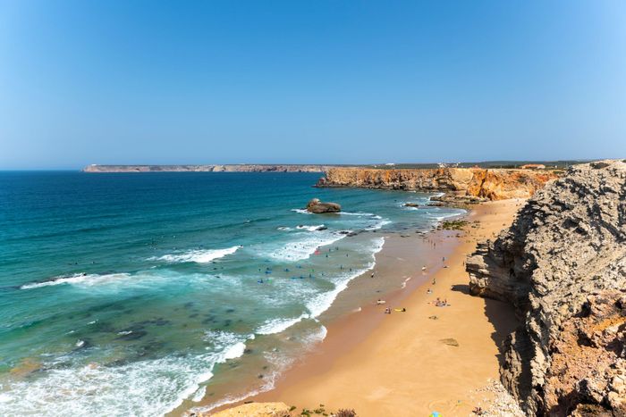 Stunning beach view of Sagres with cliffs and blue ocean under a clear sky in Faro, Portugal.