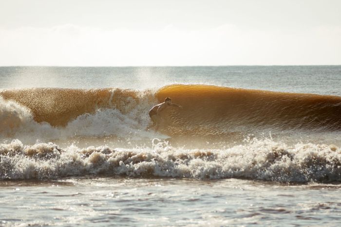 Surfer riding a massive wave on the ocean, displaying skill and balance.