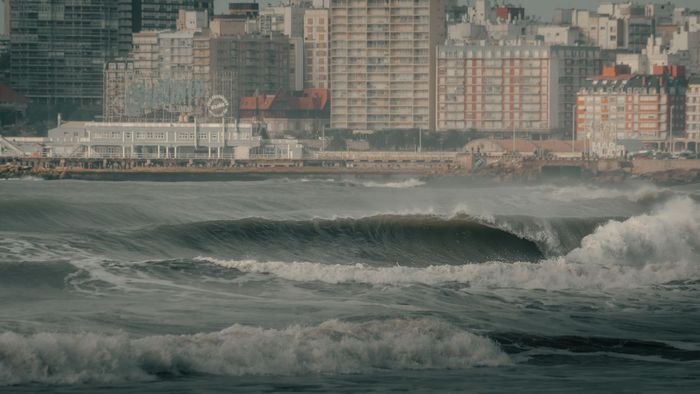 Waves crashing on the shores of Mar del Plata with the iconic skyline in the background.