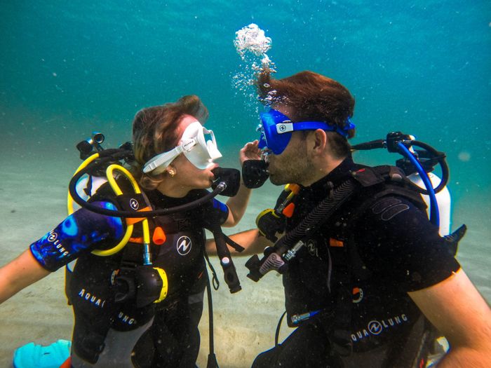 Playful couple scuba diving face to face underwater in Monopoli, Puglia, Italy.