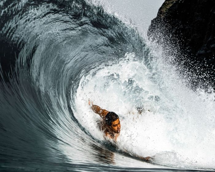 A surfer expertly navigates a powerful wave, creating an energetic splash in the ocean.