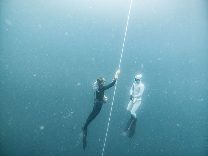 Two freedivers suspended in deep blue waters of Lombok, Indonesia, showcasing underwater exploration.