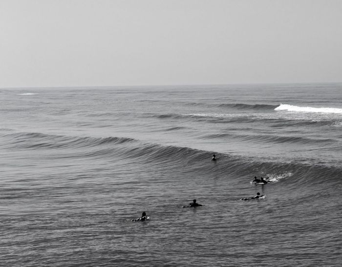 Group of surfers catching waves at Mongaguá Beach, Brazil, in sepia tones.