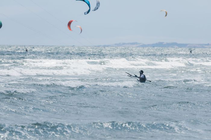 Kitesurfer skillfully navigates ocean waves, showcasing thrilling watersport dynamics.