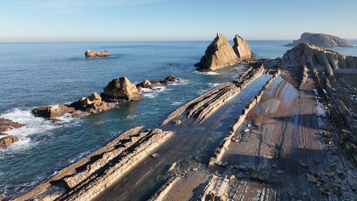 A breathtaking aerial view of Cantabria's rugged coastline with unique rock formations and clear blue sea.