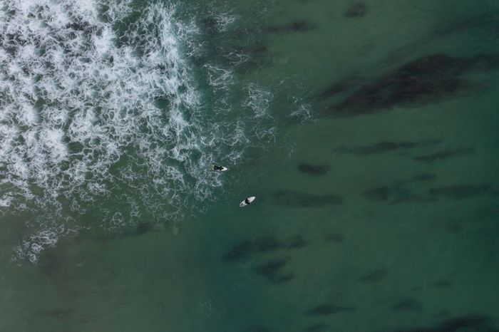 Aerial view of surfers navigating waves in Ferrel, Portugal.
