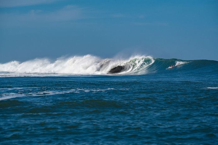A majestic wave breaks on a sunny day, showcasing the ocean's power and beauty.