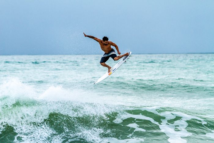 A skilled surfer performs an impressive aerial maneuver over the waves in Baía Formosa, Brazil.