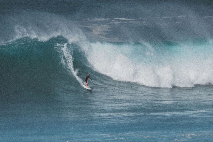 A surfer skillfully rides a giant wave at Waimea Bay, Hawaii, capturing the thrill of ocean adventure.