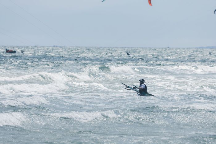 A kitesurfer tackles waves on a windy day at the sea, capturing the essence of adventure.