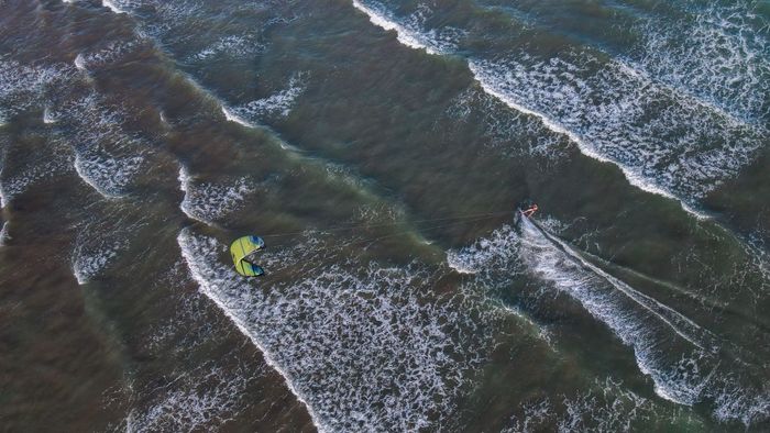 Aerial photograph of a person kiteboarding on the ocean waves in Adicora, Venezuela.