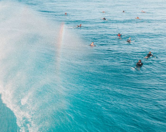 Aerial view of surfers enjoying the vibrant blue ocean with crashing waves.