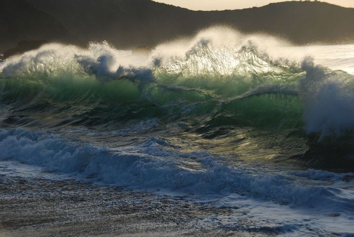 Captivating view of powerful waves crashing against the shore in Asturias, Spain, during sunset.