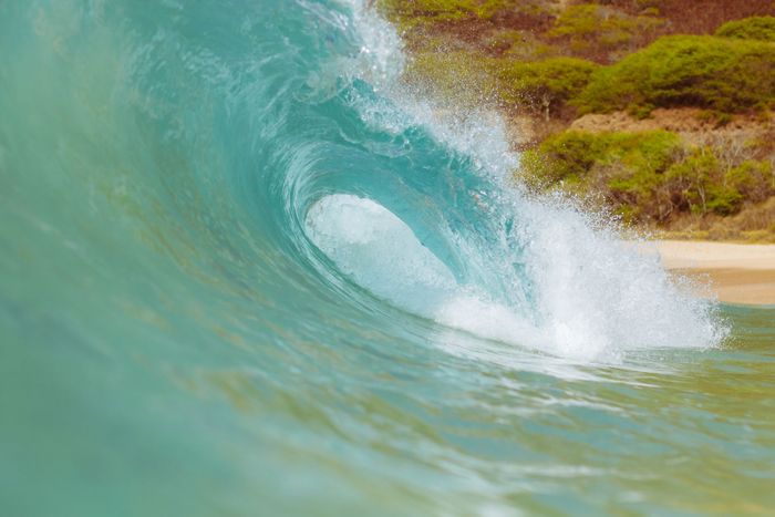 Powerful turquoise wave crashing on a pristine Hawaiian beach showcasing natural beauty.