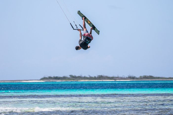 A thrilling kitesurfing trick captured mid-air over a beautiful ocean setting.