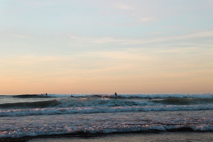 Surfers enjoying the waves during a stunning sunset in País Vasco, Spain, capturing the vibrant atmosphere.