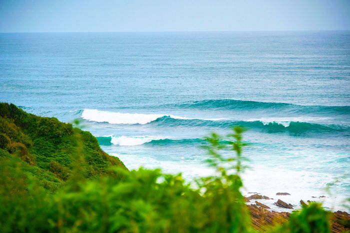 Tranquil ocean waves roll onto a lush green coastline in Saint-Jean-de-Luz.