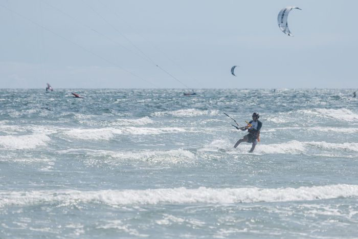 Kitesurfer enjoys the thrill of riding ocean waves on a sunny day, embodying adventure and water sports.