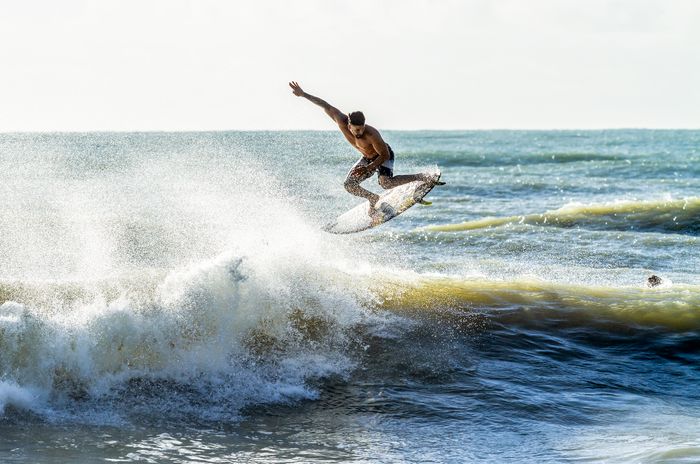 Surfer caught mid-air on a wave in Baía Formosa, Brazil, showcasing impressive skills and dynamic action.