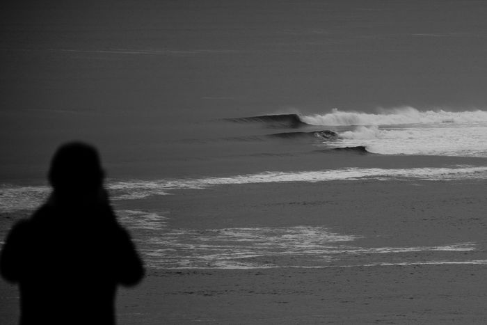 Monochrome image of a person silhouetted against ocean waves in New Zealand.