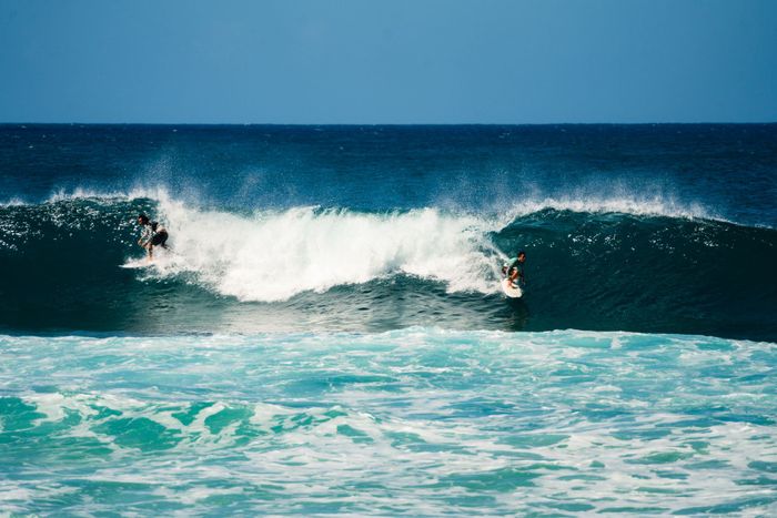 Exciting shot of two surfers riding the ocean waves under a clear blue sky.