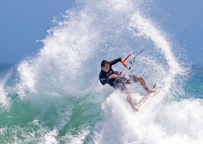 Exciting kitesurfing scene with a man riding a wave in Cape Town, vibrant motion and energy.