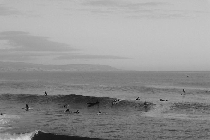 Black and white photo of surfers catching waves at Imsouane, Souss-Massa, Morocco.