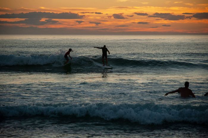 Surfers catching waves at sunset in Seignosse, France. Scenic evening by the ocean.