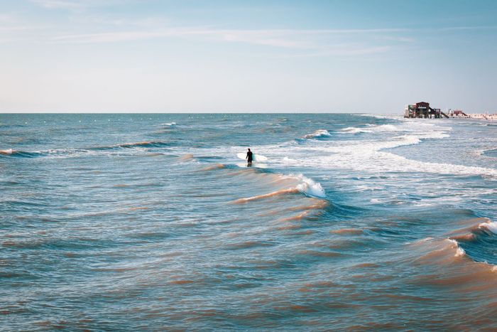 Lone surfer enjoying the azure waters and vibrant waves in Sankt Peter-Ording, Germany.